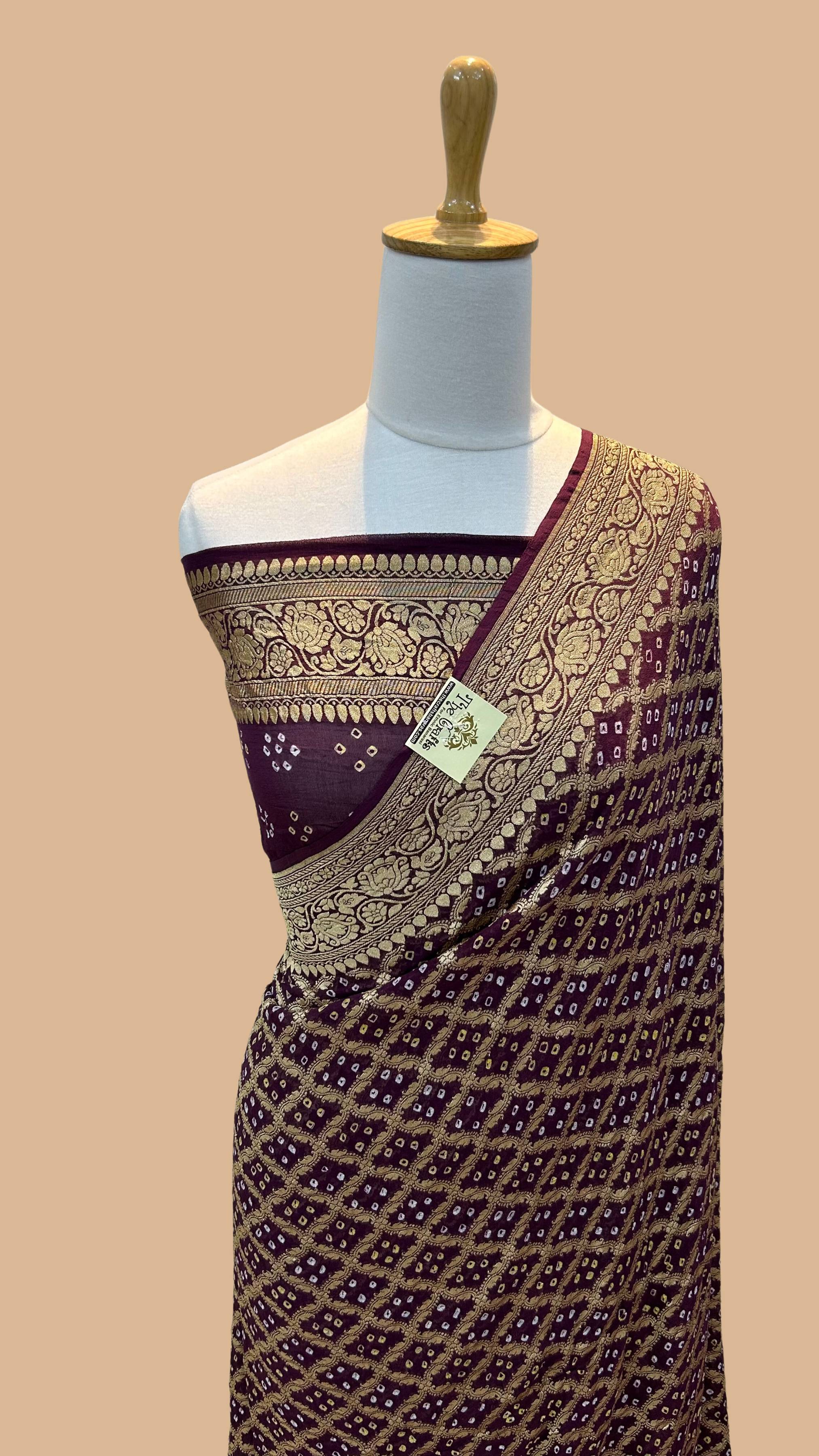 A deep wine Banarasi Bandhej saree with gold zari border, displayed on a mannequin.